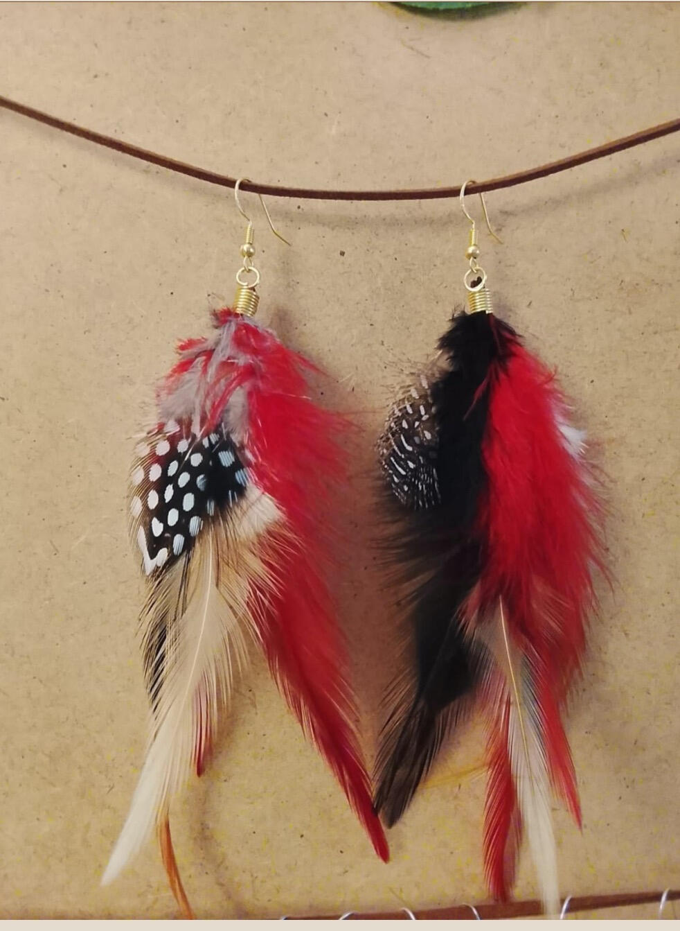 Pendientes artesanales Llama Libre con plumas rojas, negras y blancas en composición libre y expresiva